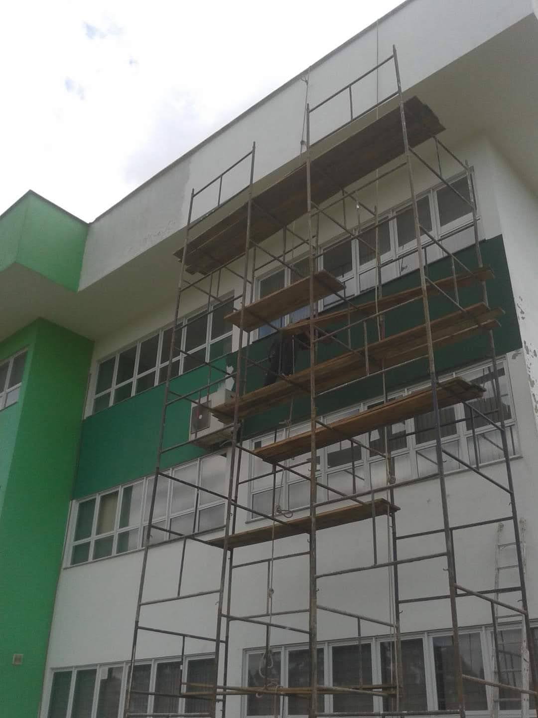 Pintura de fachada comercial em andamento com acabamento verde