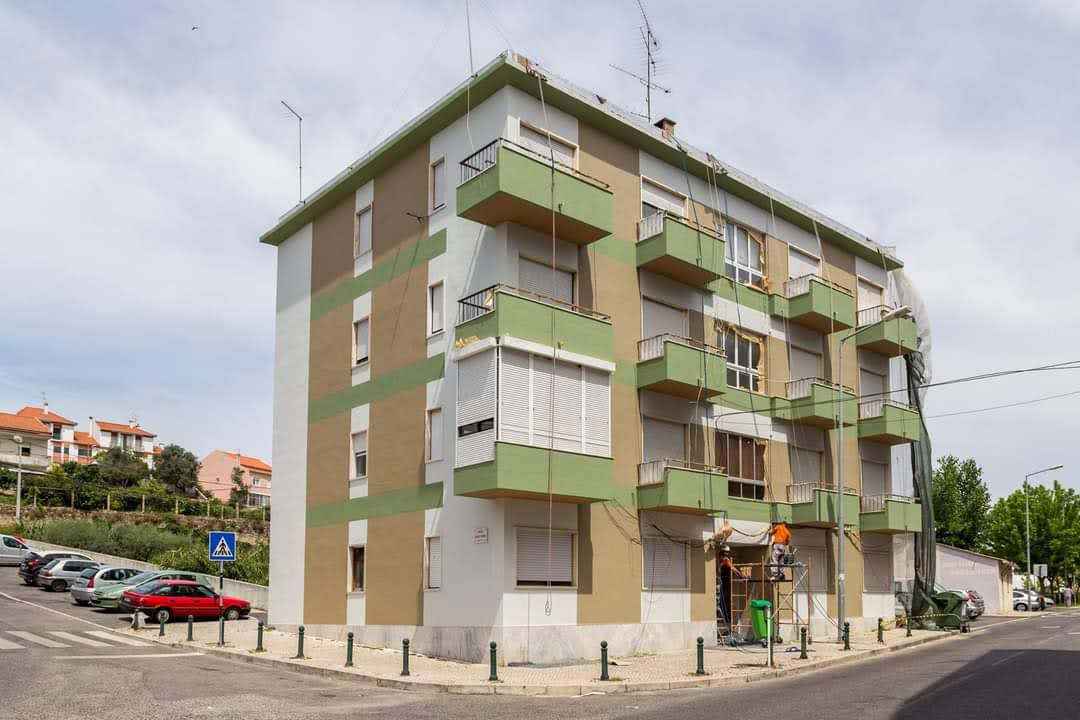 Edifício residencial recém-pintado em verde e branco com equipe em andaime