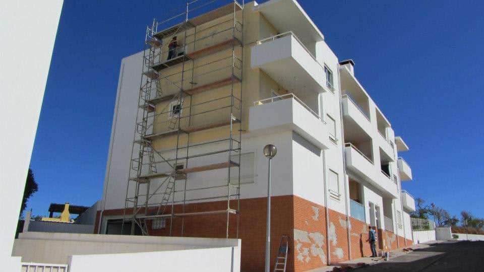 Pintura externa de fachada residencial com andaimes e equipe trabalhando