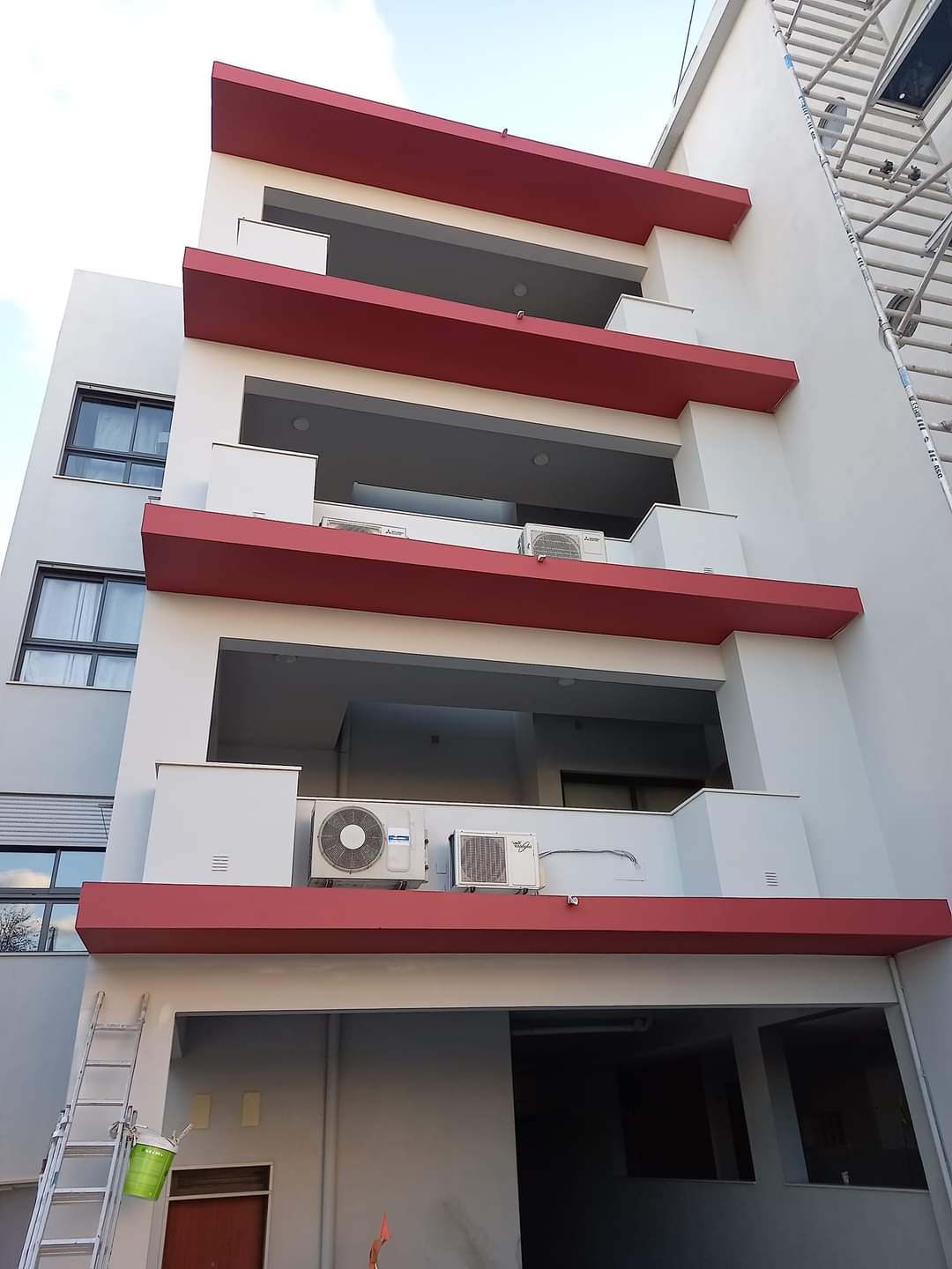 Fachada de prédio recém-pintada com detalhes em vermelho e acabamento branco e cinza